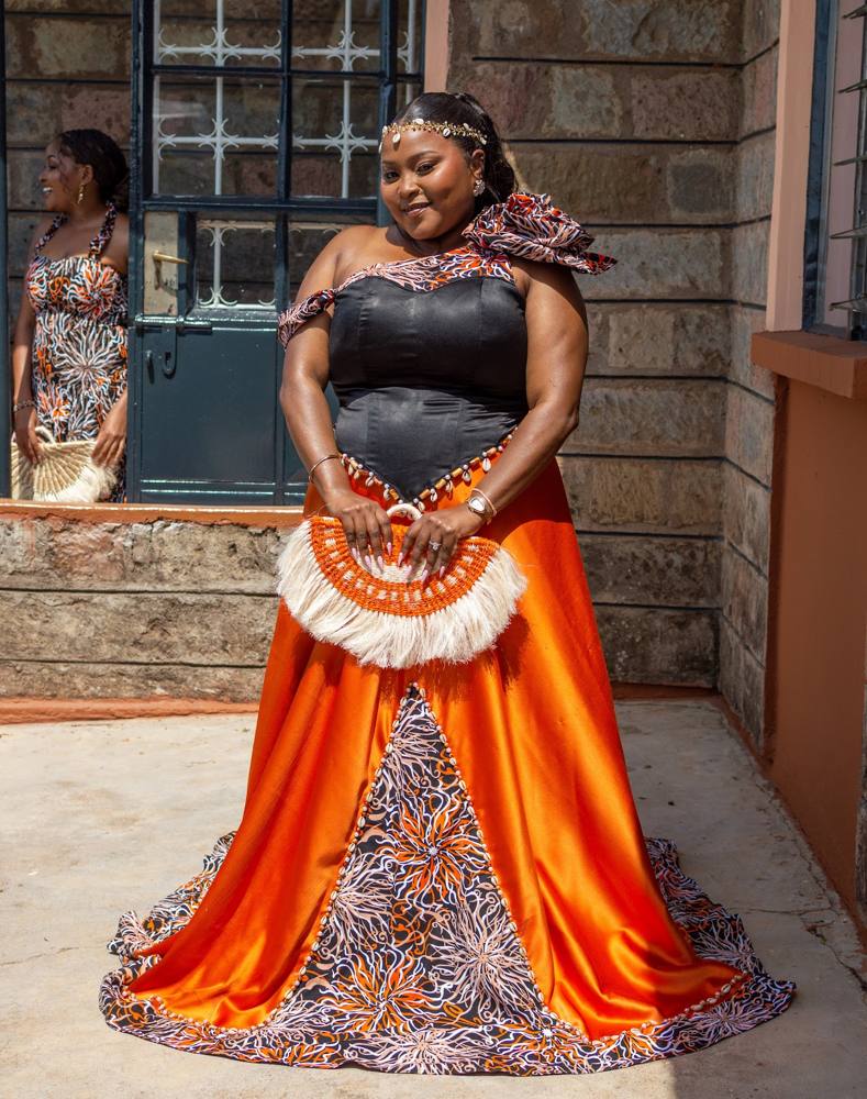 A bride in a custom orange and Ankara ruracio gown made by LoLo