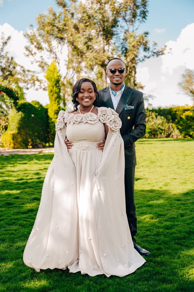 A bride and groom on a lawn, the bride in a custom caped gown
